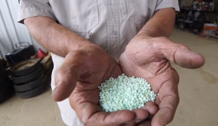 Male farmer holding green nitrogen fertilizer in his hands