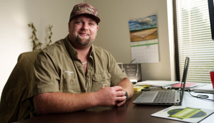 Nutrien Ag Solutions crop consultant smiling while seated at a desk with a laptop.
